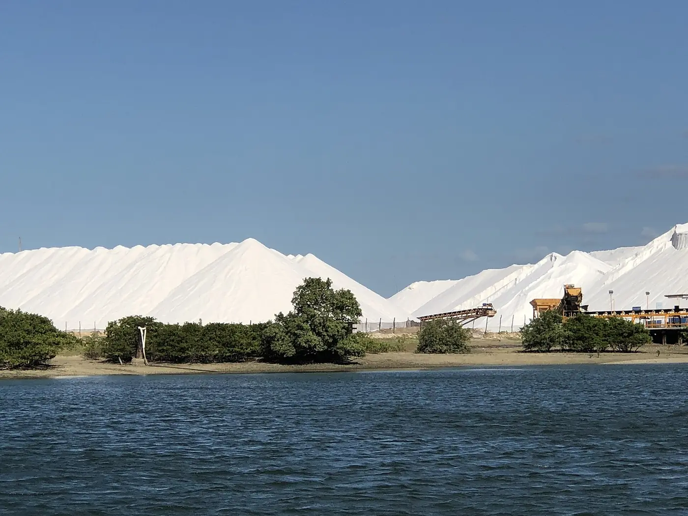Montanhas de sal marinho e maquinário na Salina Diamante Branco, em Galinhos (RN)