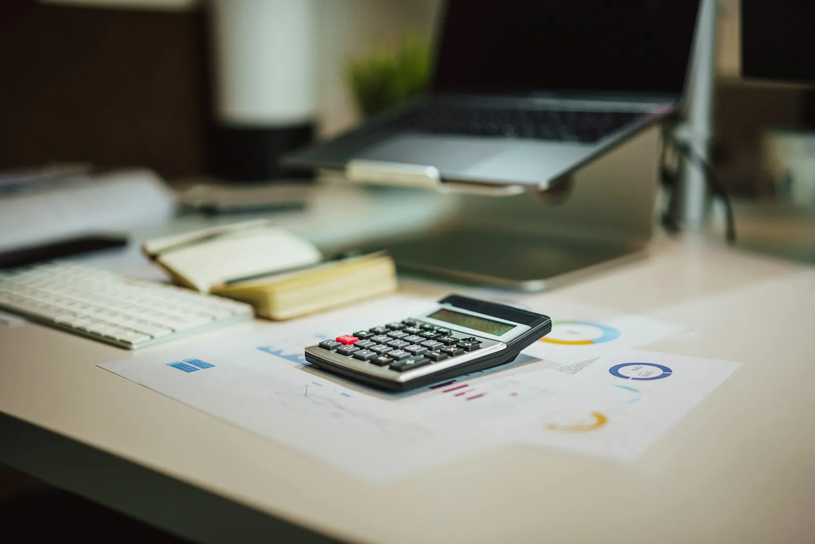 Calculadora, notebook e relatórios financeiros sobre a mesa